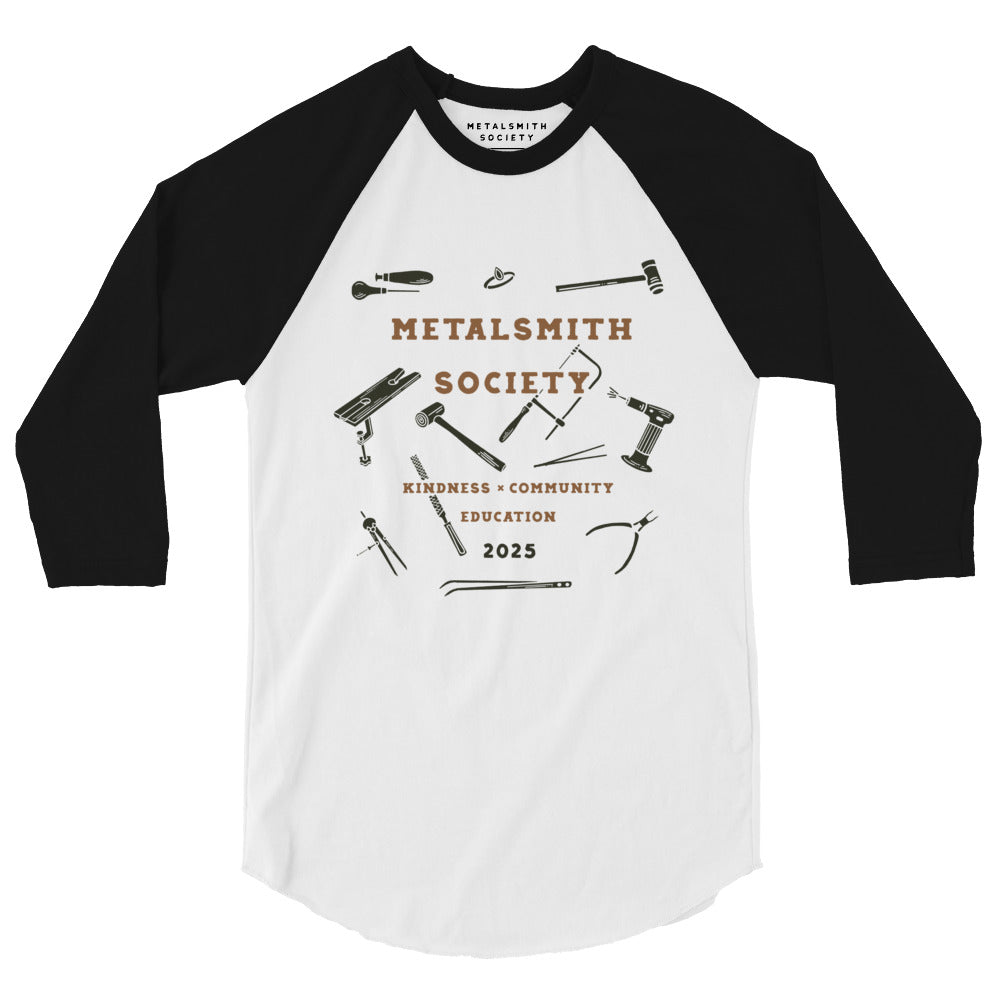 Front View of Shirt: A front-facing image of the 2025 Society Raglan Shirt featuring a white body with contrasting black raglan sleeves. The Limited Edition 2025 Metalsmith Society's logo is prominently displayed on the chest with illustrations of jewerlry tools.