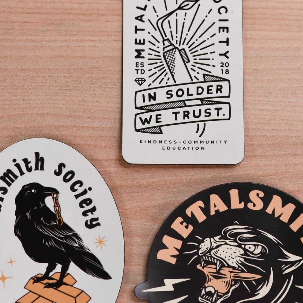 Three metalworking-themed magnets on a wooden surface