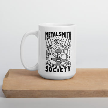 This white mug with a black design  features the limited edition 2024 design created by Boring friends for Metalsmith Society. It depicts jewelry making tools!
